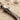 Bird letter I pendant, close-up view of bird head and feathers on sand