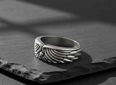 Side profile of handcrafted silver plumage ring highlighting band thickness and comfortable fit on stone surface