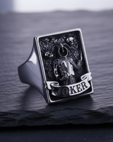 Silver Joker ring featuring gothic jester holding a skull with floating skulls on stone surface