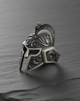 Oxidized 925 sterling silver Spartan helmet ring showing detailed engravings and a dark, antiqued finish on a slate backdrop.