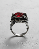 Front view of 925 sterling silver ring with three graces design holding a red cabochon stone on grey background