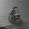Oxidized Silver Spartan Helmet Ring showcasing intricate scrollwork engravings on a textured dark slate surface.