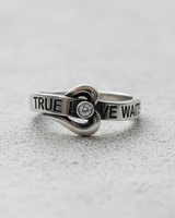 Close up of crystal stone setting inside heart shape on silver True Love Waits band ring