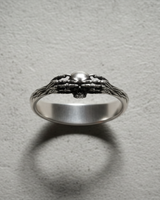 Close-up of handcrafted silver skull ring with gnarled bone texture band and intricate dark aesthetic details