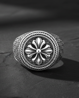 Top view of silver signet ring showing detailed relief of the floral cross motif and textured border
