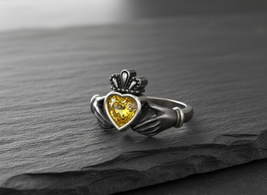 925 sterling silver Claddagh ring with yellow heart gemstone and crown detail on dark background