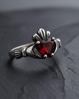 Close-up of red heart shaped gemstone and silver crown design on a vintage style Celtic Claddagh ring