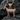 Detailed side view of the sparkling rose gold plated goat pendant resting on dark rocks, highlighting intricate metalwork