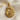 Close-up of the handcrafted lion head pendant showing detailed relief carving and rich gold vermeil on linen cloth