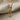 Close-up view of a luxury gold vermeil safety pin pendant resting gracefully on a textured beige fabric surface