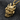 Close-up of premium gold vermeil samurai mask pendant resting on dark textured fabric highlighting metal craftsmanship