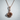 Rose Thorn Pendant, rose gold, front view against wall