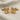 Close-up of 925 sterling silver Luwian hieroglyph cufflinks with gold finish resting on a textured linen background
