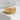 Side view of gold royal crown band resting on light gray textured pedestal highlighting gothic crown arches