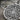 Close-up macro shot of handcrafted oxidized silver Aztec sun pendant detailing intricate relief carvings