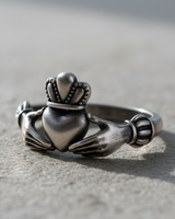 Handcrafted 925 sterling silver Claddagh ring featuring hands holding a crowned heart design on textured surface