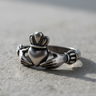 Handcrafted 925 sterling silver Claddagh ring featuring hands holding a crowned heart design on textured surface