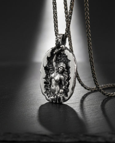 Angled view of handcrafted silver pendant showing black rhodium plating and textured rock details