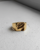 Gold vermeil on silver rift signet ring featuring textured jagged center design on grey surface