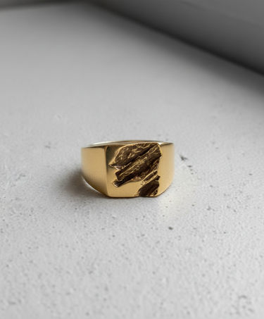 Gold vermeil on silver rift signet ring featuring textured jagged center design on grey surface