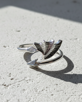Top view of 925 sterling silver bat wing ring with arrow tail detail on textured background