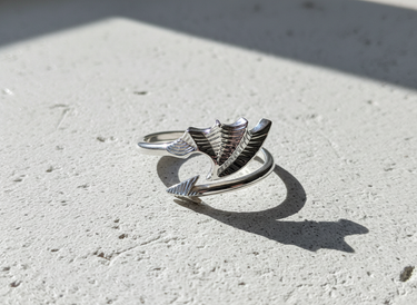 Top view of 925 sterling silver bat wing ring with arrow tail detail on textured background