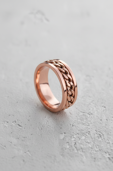 Rose gold plated 925 sterling silver ring with rotating curb chain center displayed on textured surface
