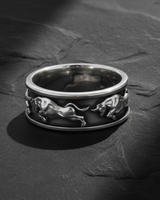 Close up of handcrafted silver taurus ring band displaying dynamic running bull motifs and texture