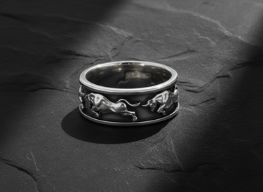 Close up of handcrafted silver taurus ring band displaying dynamic running bull motifs and texture