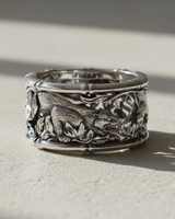 Detailed close-up of handcrafted silver ring with tiger wandering through bamboo forest setting