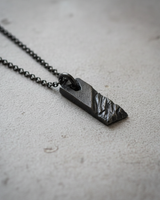 Handcrafted Silver Rustic Bar Pendant featuring black rhodium plating and textured surface on concrete background