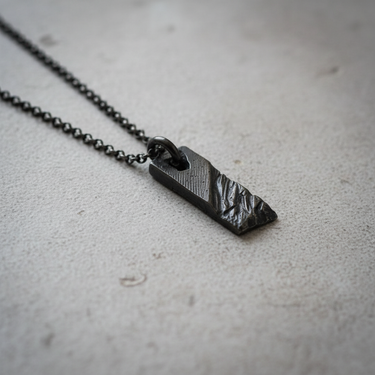 Handcrafted Silver Rustic Bar Pendant featuring black rhodium plating and textured surface on concrete background