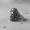 Side profile of silver Greek god ring showing iconic trident symbol and swirling wave textures on the band