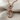 Close-up of the polished treble clef pendant resting on a soft beige textured fabric highlighting its smooth curves