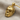 Close-up angled shot of the handcrafted masked skull pendant resting on textured fabric showing detailed metalwork.