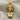 Close-up of golden Medusa head pendant resting on textured fabric highlighting the sculpted face and serpentine details