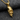 Close-up of the handcrafted broken skull pendant in gold resting on textured grey fabric highlighting bone details