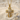 Close-up of premium diamond cross pendant resting on sand, showcasing detailed stone setting and gold craftsmanship.