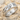 Close-up of the handcrafted sterling silver woven ring resting on sand and seashells highlighting the polished finish