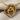Detailed view of gold motherhood heart pendant resting on beige linen fabric highlighting the craftsmanship