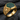 Close-up of gold vermeil blacksmith ring resting on dark slate stone showing intricate textured anvil and hammer