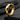 Close-up of geometric hoop earring with light catching the sharp angled facets resting on dark slate stone