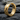 Close-up of minimalist geometric hoop earring displaying sharp angular facets resting on dark textured stone