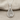 Detailed silver tennis racket pendant with ball resting flat against a textured beige fabric background