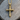 Close-up of the two-sided gold nail cross pendant resting beautifully on a naturally textured wooden surface.