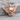 Outspread Winged Skull Pendant, rose gold finish, angled view on wood base