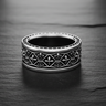 Silver Fleur-de-lis Cross Ring with an oxidized finish and milgrain edges, showcased on a dark, textured slate surface.