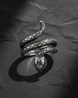 High-angle view of 925 sterling silver snake ring showing coiled design and textured scales on dark stone background