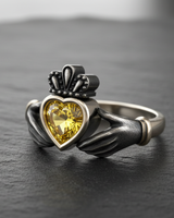 Close-up of intricate crown and hand details on sterling silver Claddagh ring with yellow gem