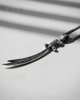 Side view of handcrafted Islamic sword necklace showing hilt detail and black chain connection